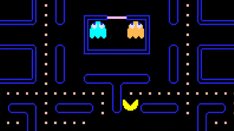 A Pac-Man pontokat fogyaszt, miközben kék és narancssárga szellemek ülnek a Pac-Man cellájában