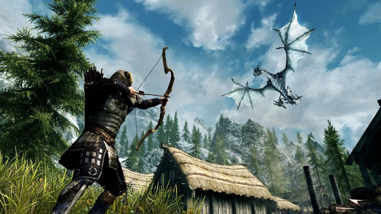 A játékos karakter egy nyilat céloz egy falu felett repülő sárkányra a The Elder Scrolls V: Skyrimben.