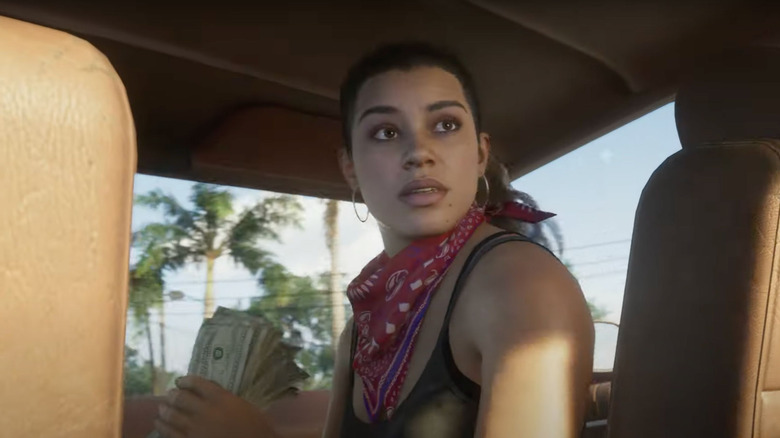 Lucia Caminos hátranéz egy autóban, miközben egy köteg dollár bankjegyet tart a kezében a Grand Theft Auto 6-ban