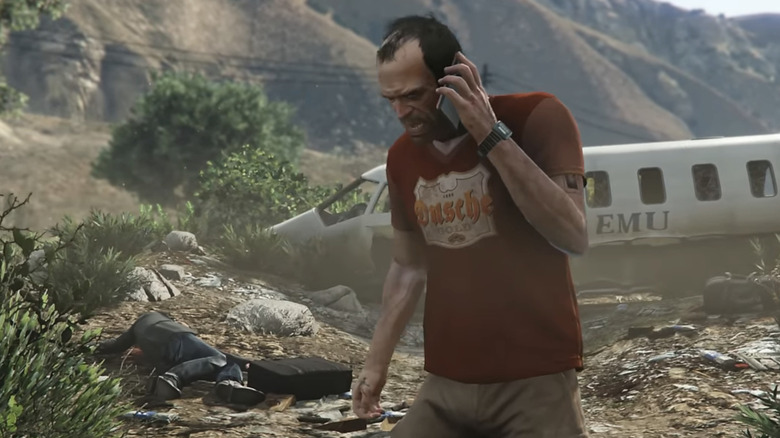 Trevor Phillips mobiltelefonon beszél egy lezuhant repülőgép előtt a Grand Theft Auto 5-ben