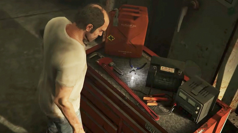 Trevor Phillips egy sor kínzófegyver közül válogat egy szerszámosládán a Grand Theft Auto V-ben