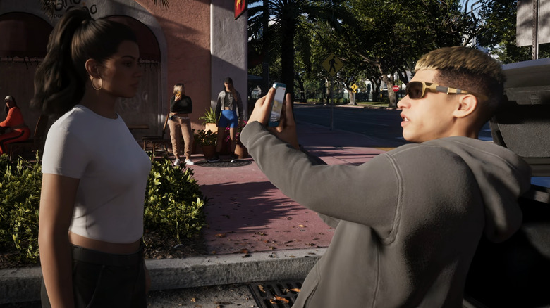 Egy férfi Lucia elé tartja a telefonját a Grand Theft Auto 6-ban