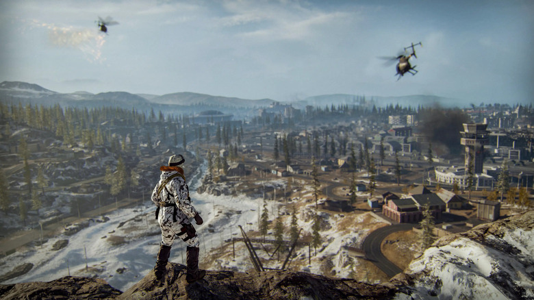 Egy katona két helikoptert néz egy erdő felett a Call of Duty: Warzone-ban