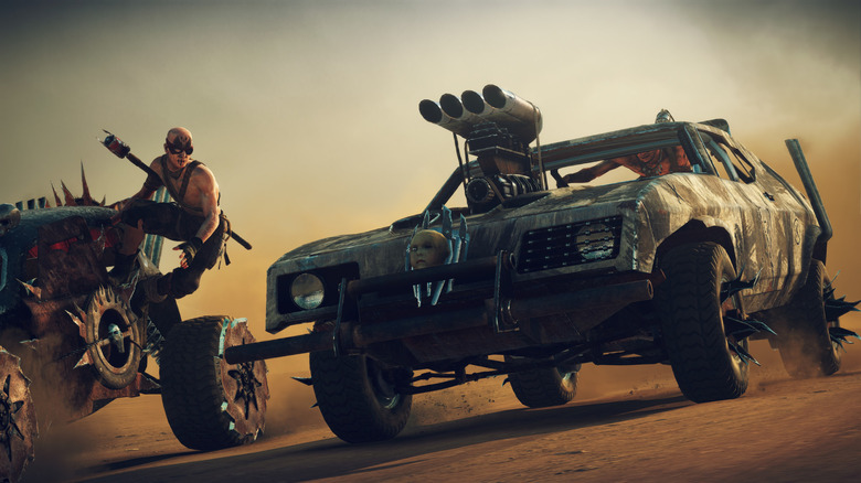 Két autó egymás mellett száguld egy földes autópályán a Mad Maxban