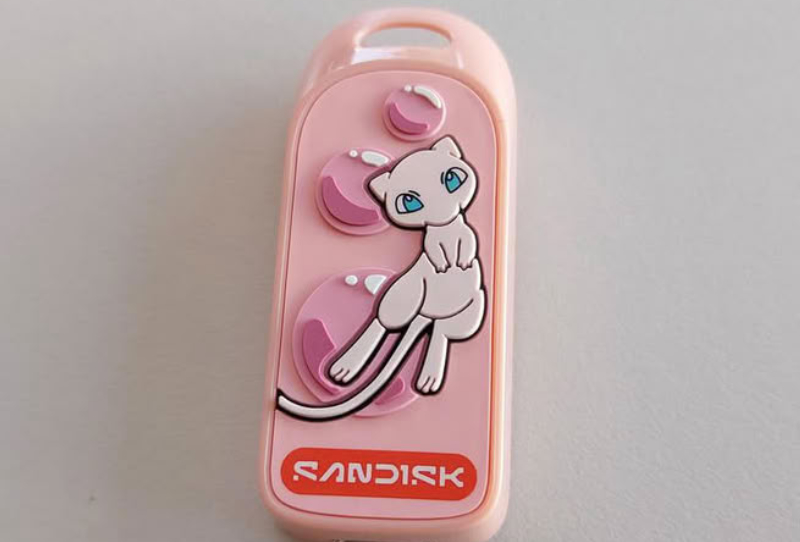 Sandisk Pokémon Portable SSD in Mewtwo edition next to the Mew-themed USB-C flash drive