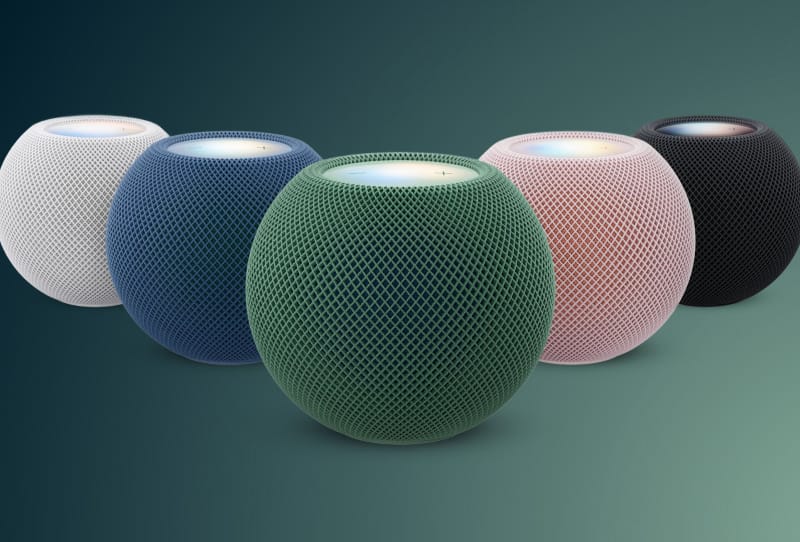 Apple HomePod mini 2 smart speaker in a two-tone pink finish on a wooden shelf